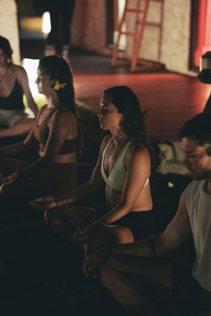 our-story A serene indoor yoga session with adults meditating in low light to promote relaxation and mindfulness.