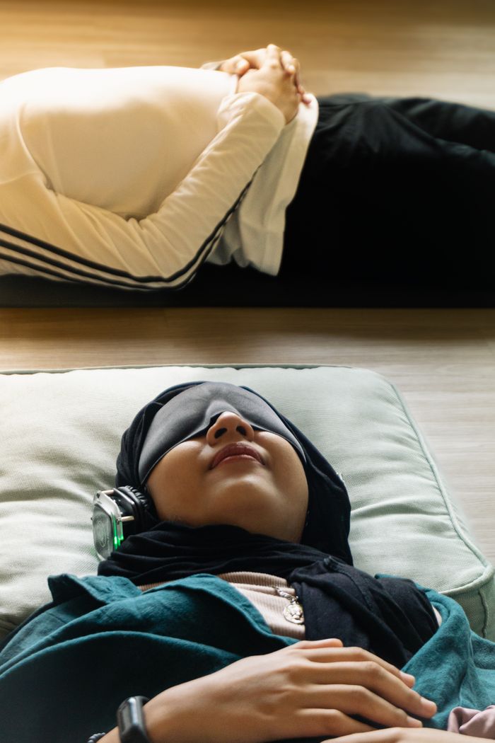 services-01 Adults relaxing indoors with eye masks and headphones, meditating in peaceful setting.