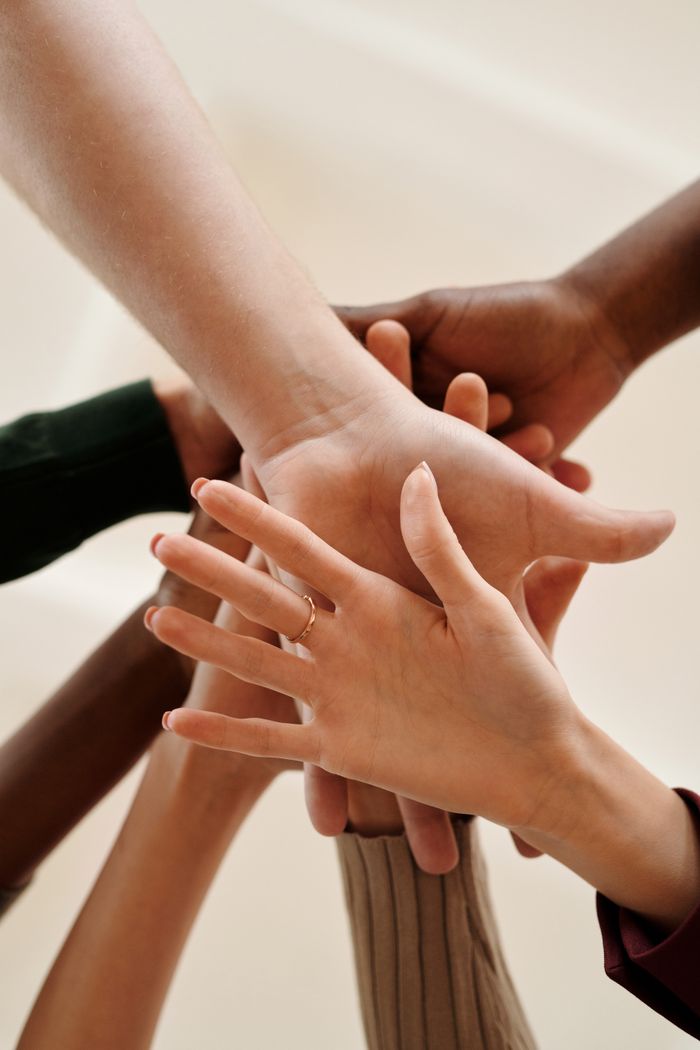 Mastering the First Impression: Your intriguing post title goes here A close-up of diverse hands joined together symbolizing teamwork, cooperation, and unity indoors.