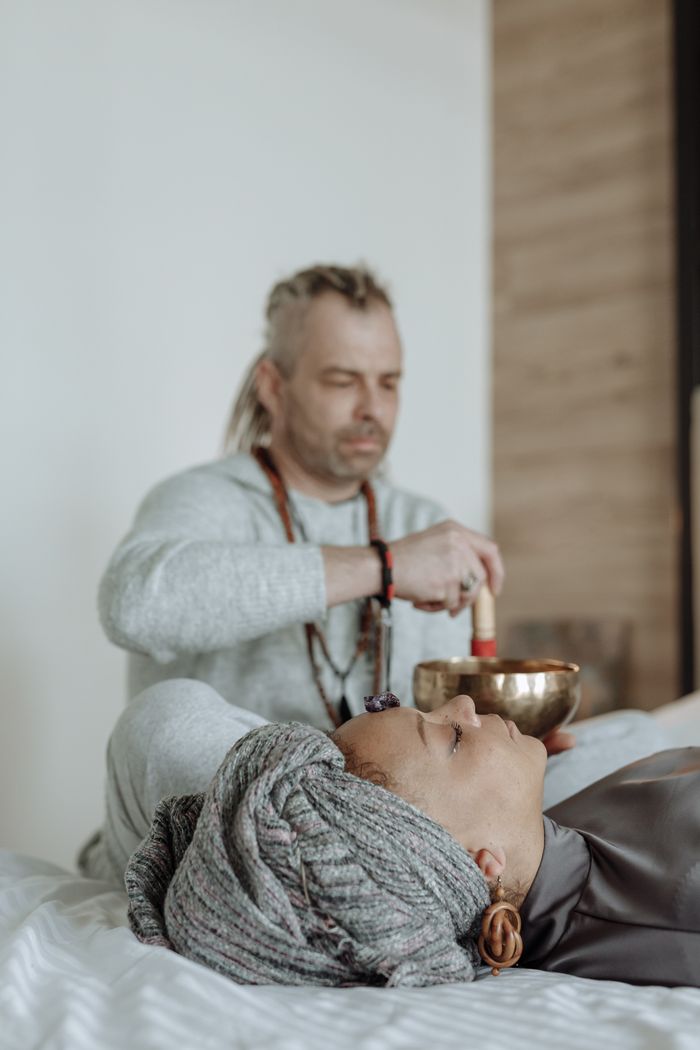 services-02 A person uses a singing bowl in a calming sound therapy session, promoting healing and relaxation.